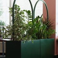 Ożywiające zielone rośliny   Istotnym elementem koncepcji wnętrza jest uzupełnienie pudrowej kolorystyki o głęboką zieleń. Projektantki posłużyły się mobilnymi ściankami uzupełnionymi zielonymi roślin